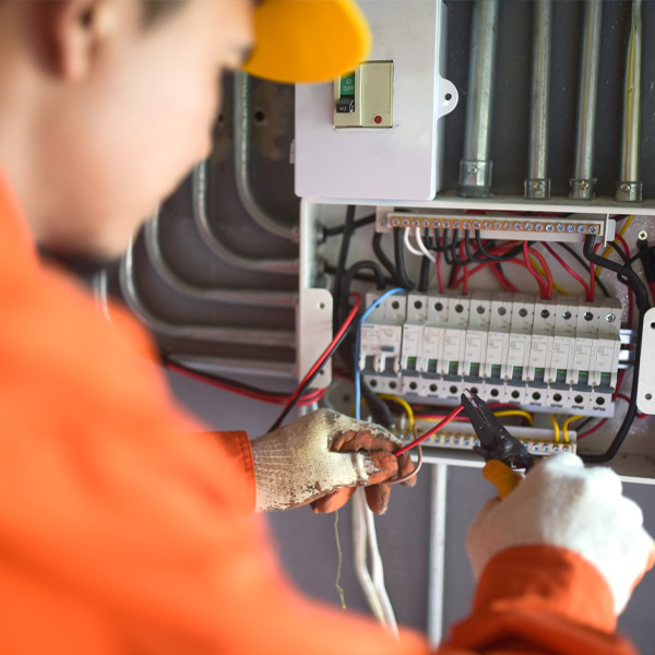 professional in orange work uniform working on electrical wiring